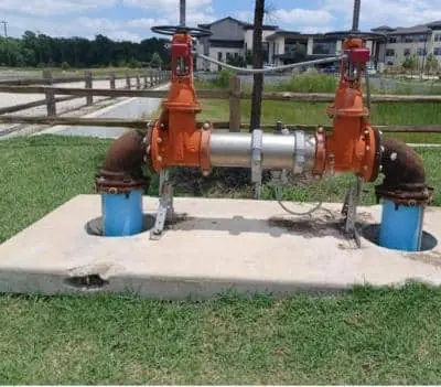 Outdoor backflow preventer with orange valves on a concrete pad